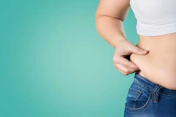 Image of woman pinching her love handles to show weight gain Edgware